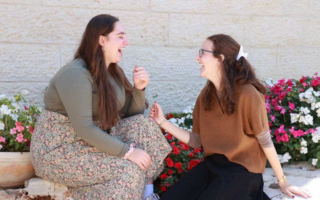 Two women laughing together by flowers