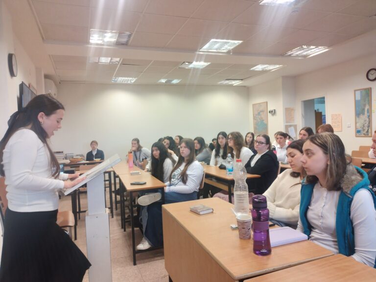 Female lecturer addressing attentive students in classroom