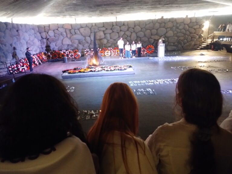 Three visitors observing memorial with eternal flame