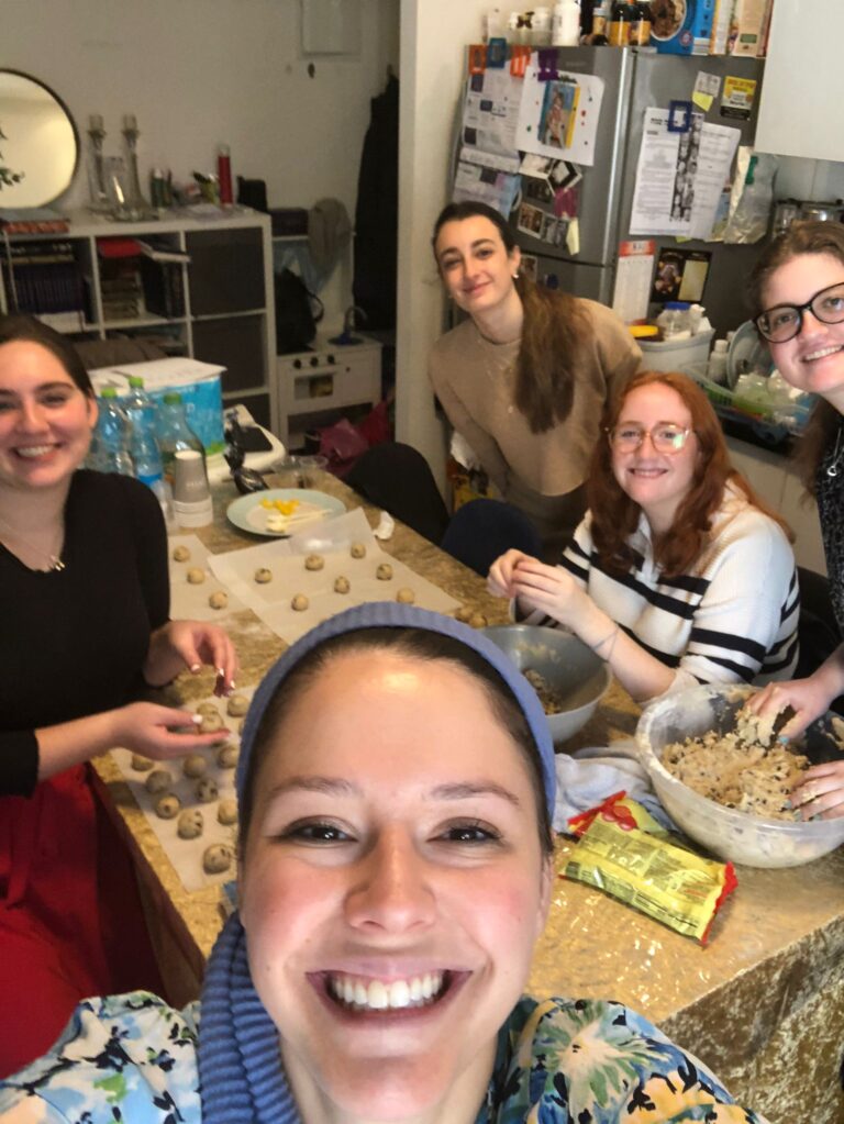 Group of friends rolling dough at kitchen table