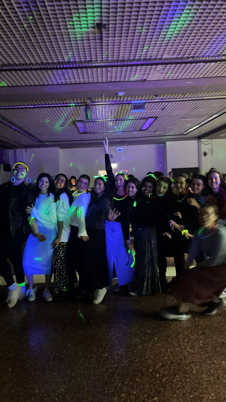 Group posing under purple and green disco lights