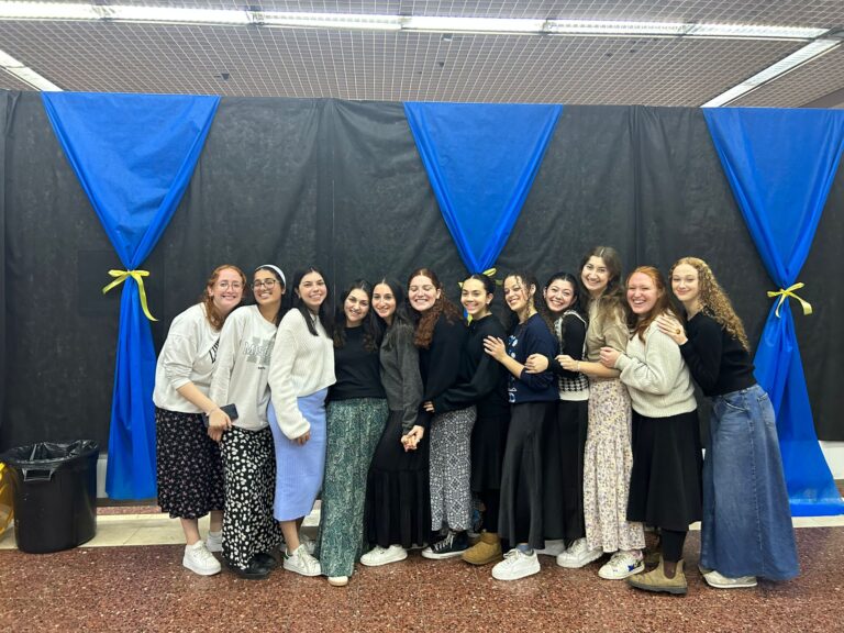 Group photo of smiling women with blue backdrop