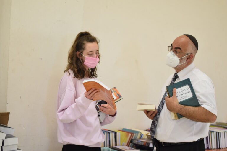 Two masked people holding books in bookstore