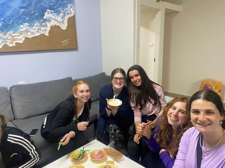 Five friends smiling around a dessert table