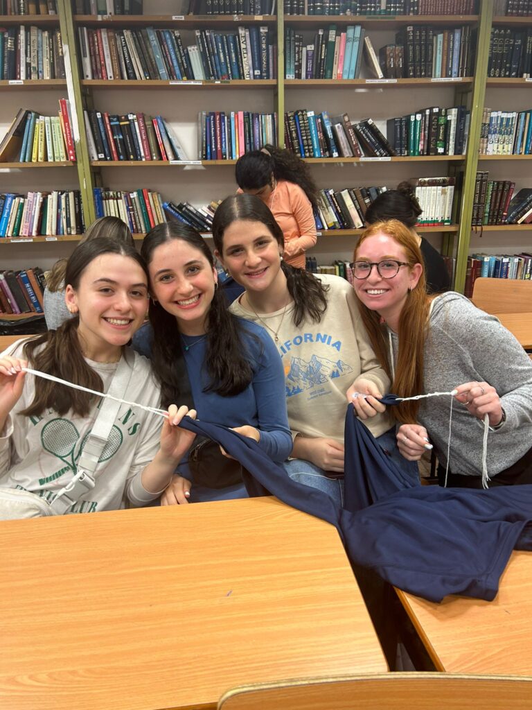 Four smiling women sewing together in library