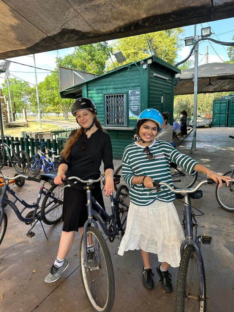 Two women wearing helmets with bicycles