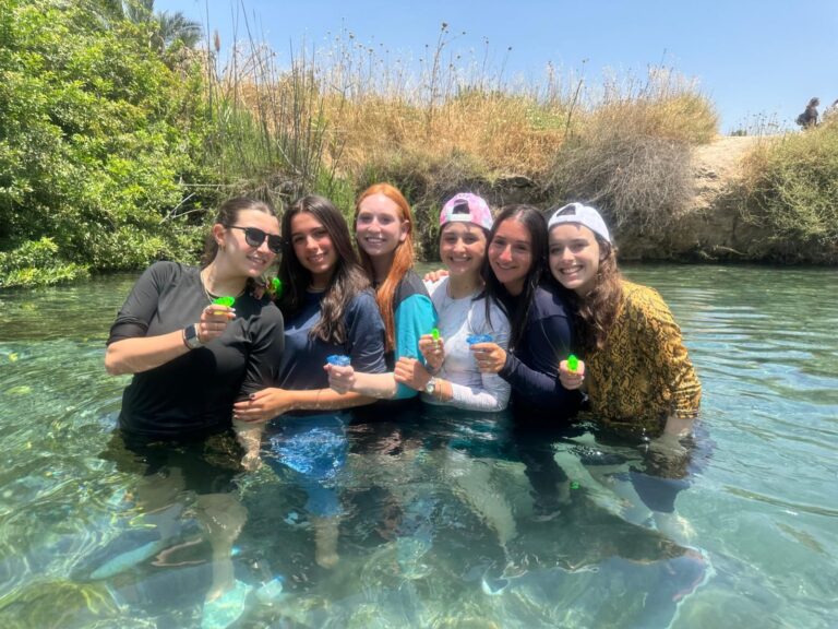 Six friends smiling in clear river water