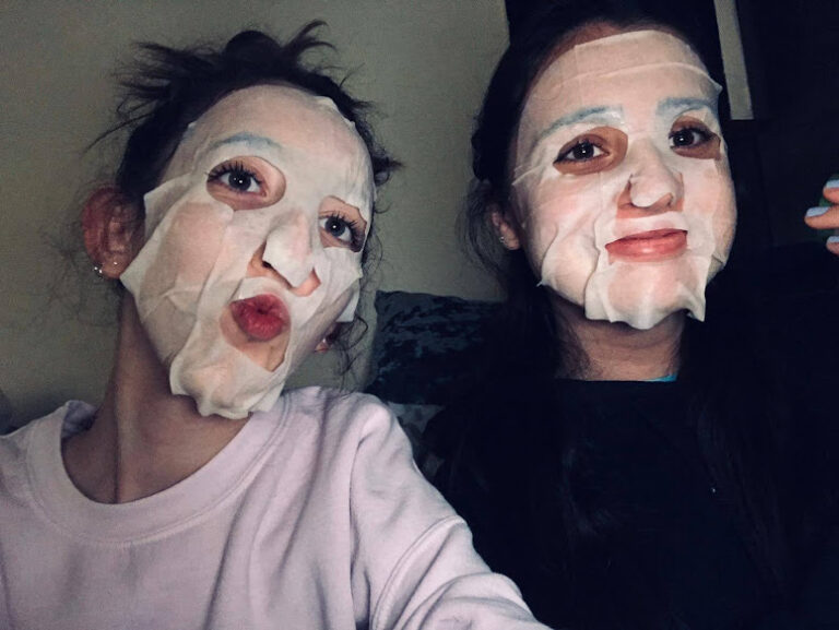 Two people wearing sheet face masks posing