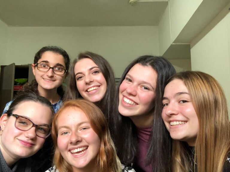 Indoor group selfie of six smiling friends