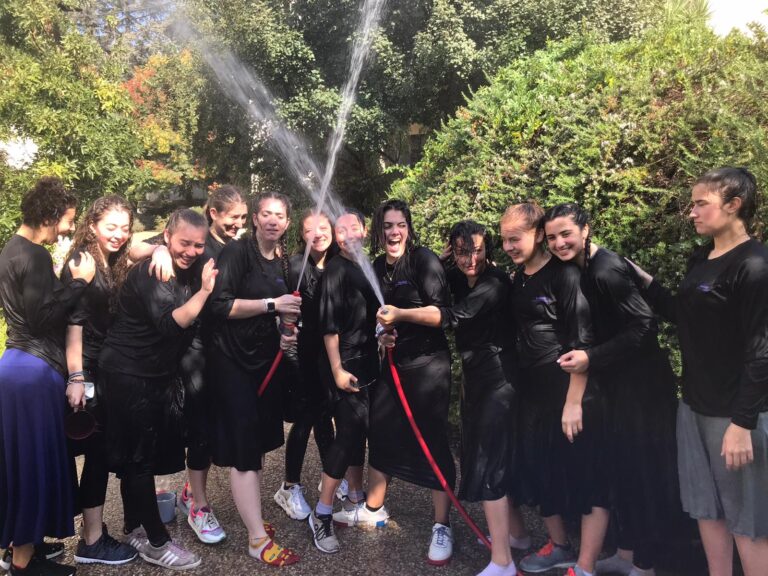 Group of people laughing under spraying water hoses