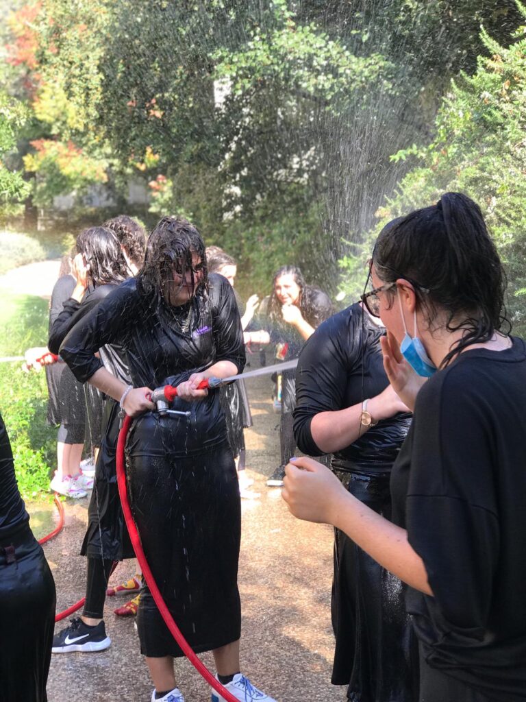 Group getting soaked by garden hose outdoors