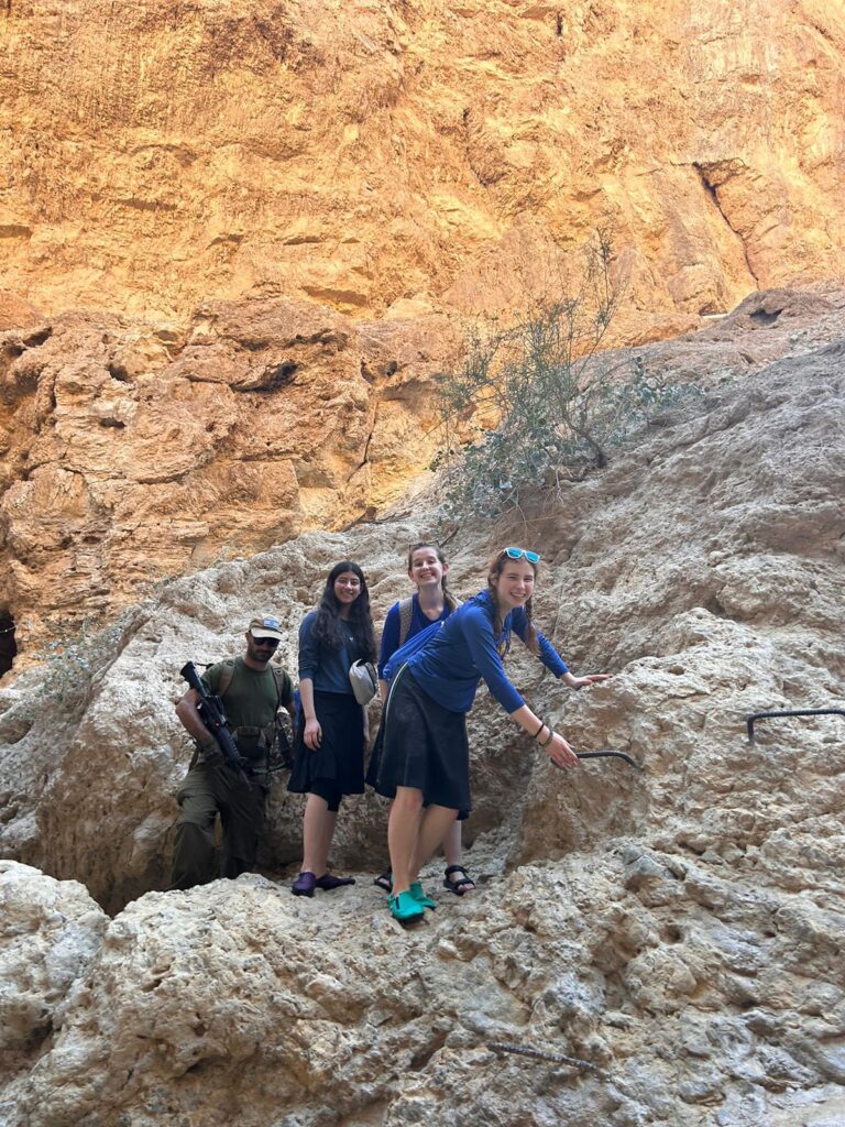 Three hikers with armed escort in rocky canyon