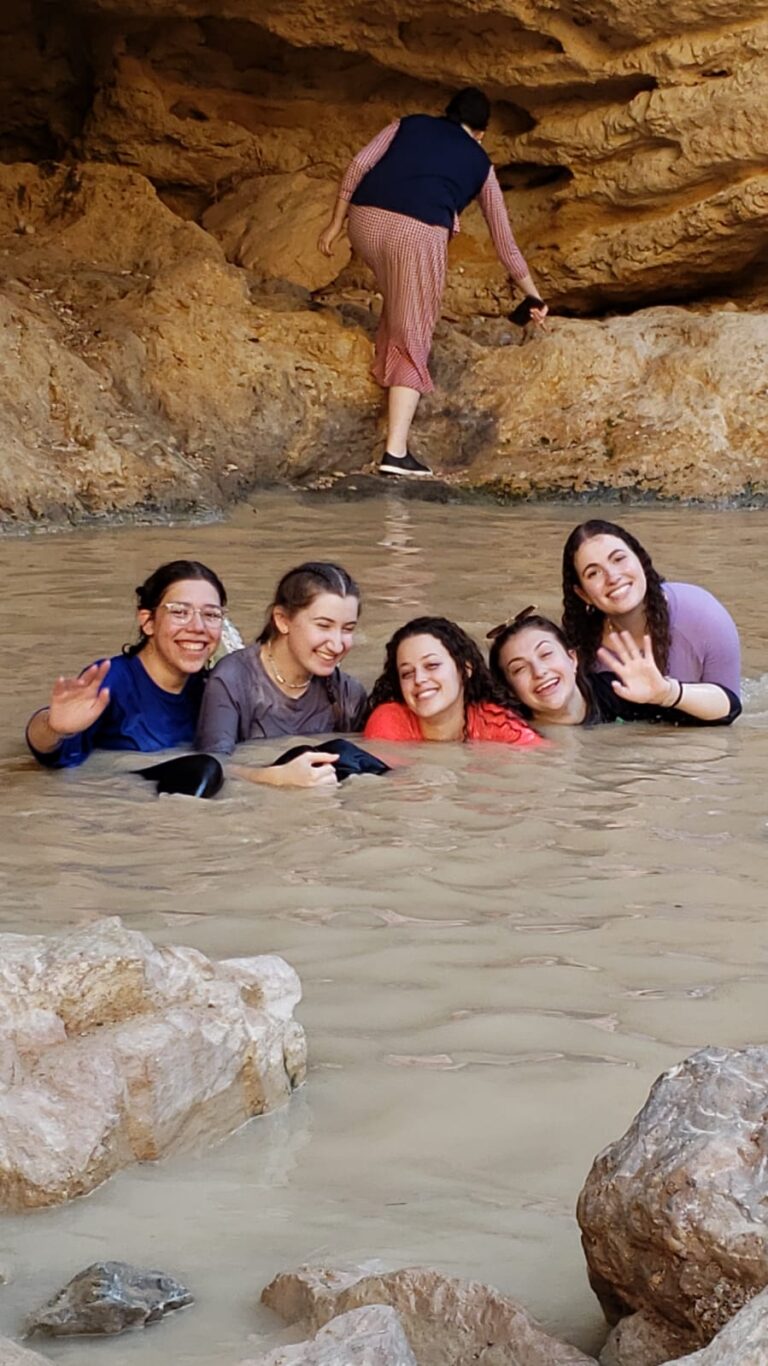 Group of friends wading in muddy cave pool
