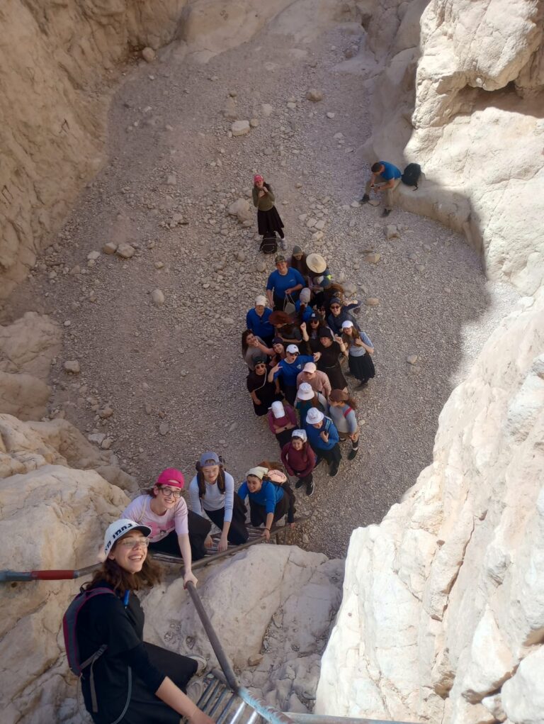 Group of hikers climbing narrow rocky canyon