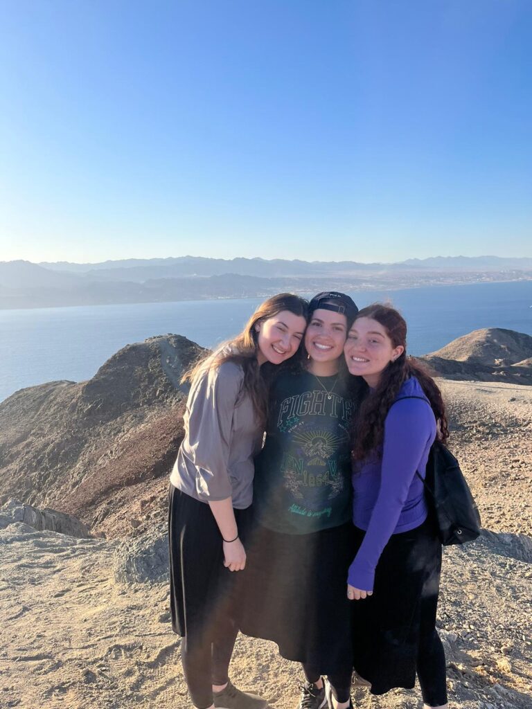 Three friends smiling on seaside hilltop
