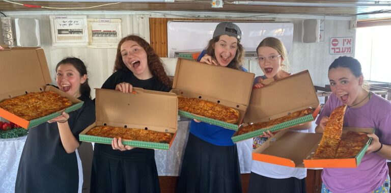 Playful group of young women holding pizza boxes