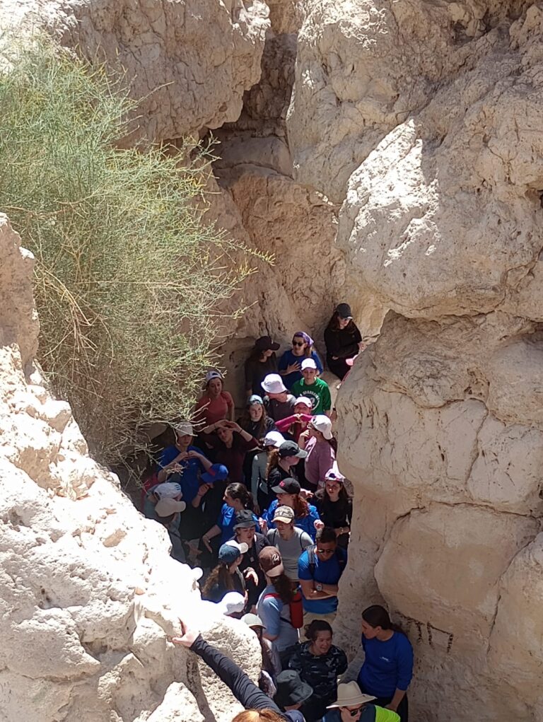 Group hiking through narrow sunlit desert canyon