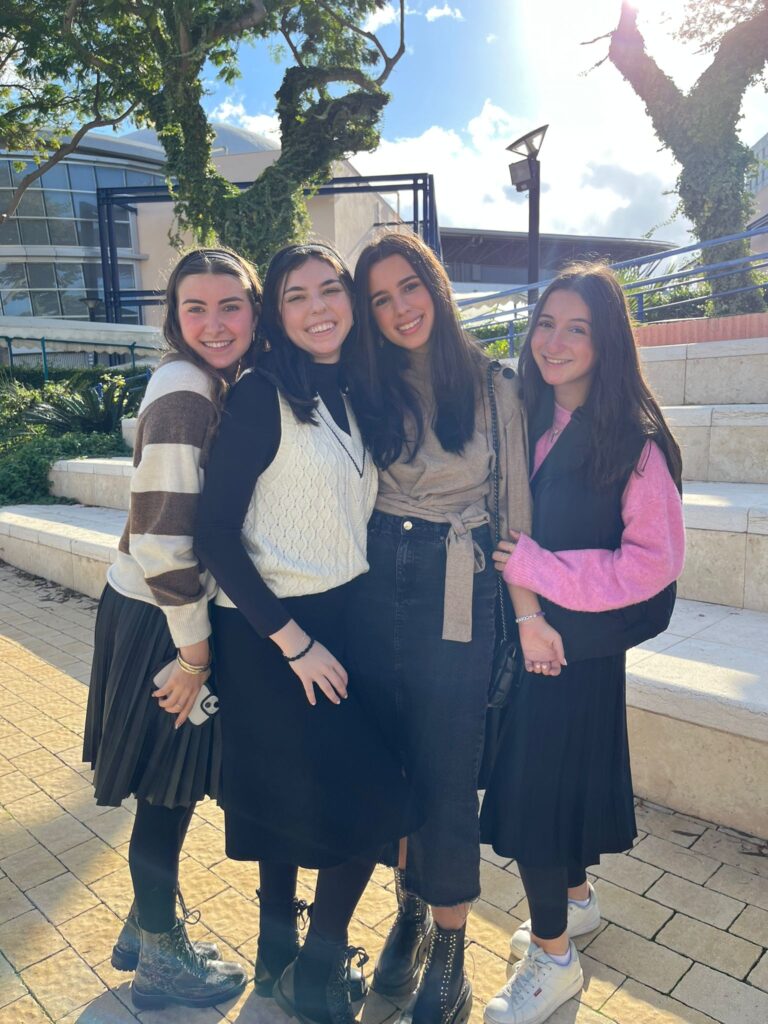 Four smiling women standing together outdoors