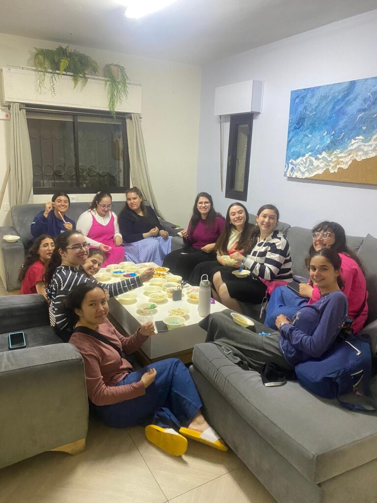 Women gathered around living room table sharing snacks