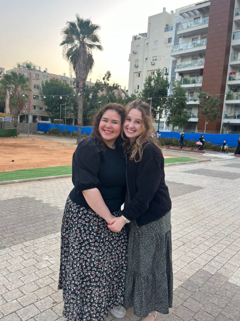 Two women smiling and embracing outdoors