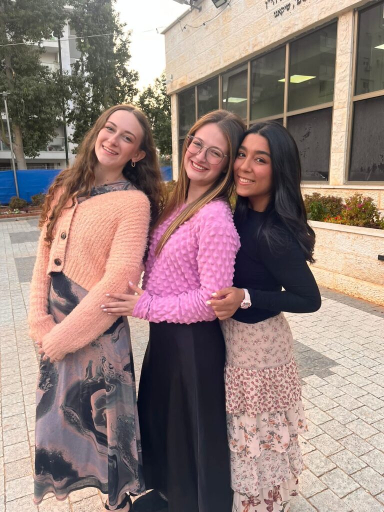 Three smiling young women standing outdoors