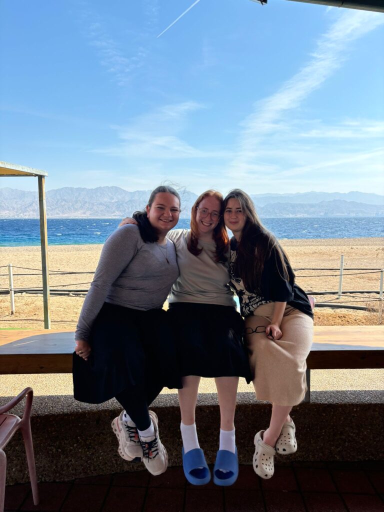 Three friends sitting on a beach bench