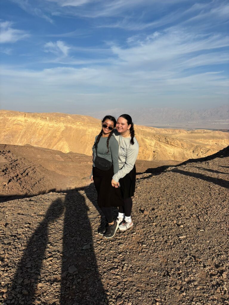 Two women smiling on rocky desert overlook