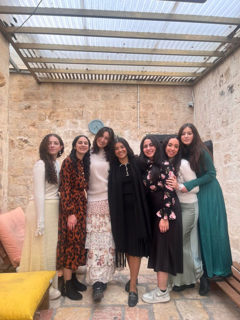 Seven women smiling in courtyard under glass roof