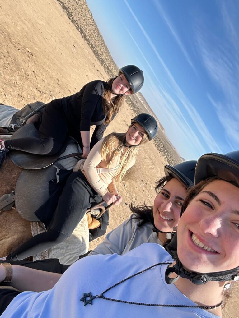 Four smiling riders taking a desert selfie