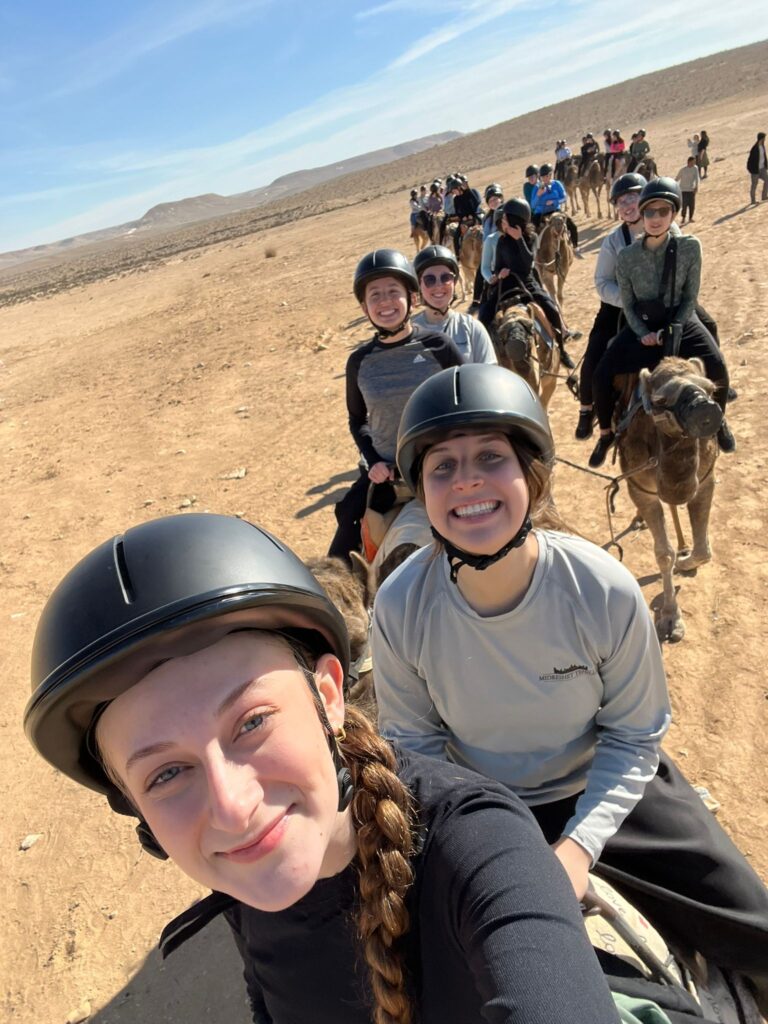 Group of smiling riders on camels in desert