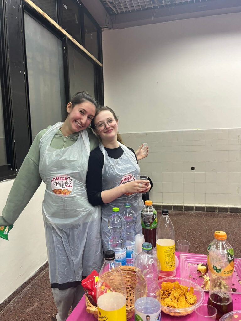 Two smiling women in aprons behind table