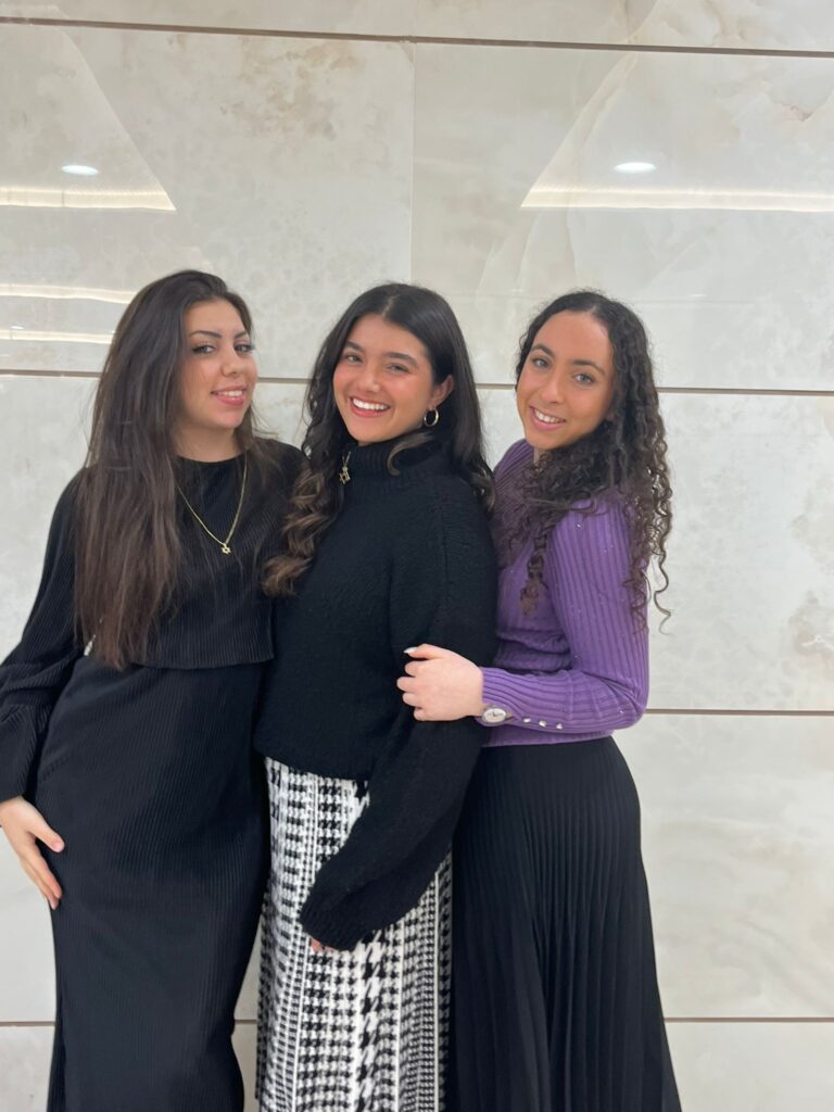 Three smiling young women posing indoors