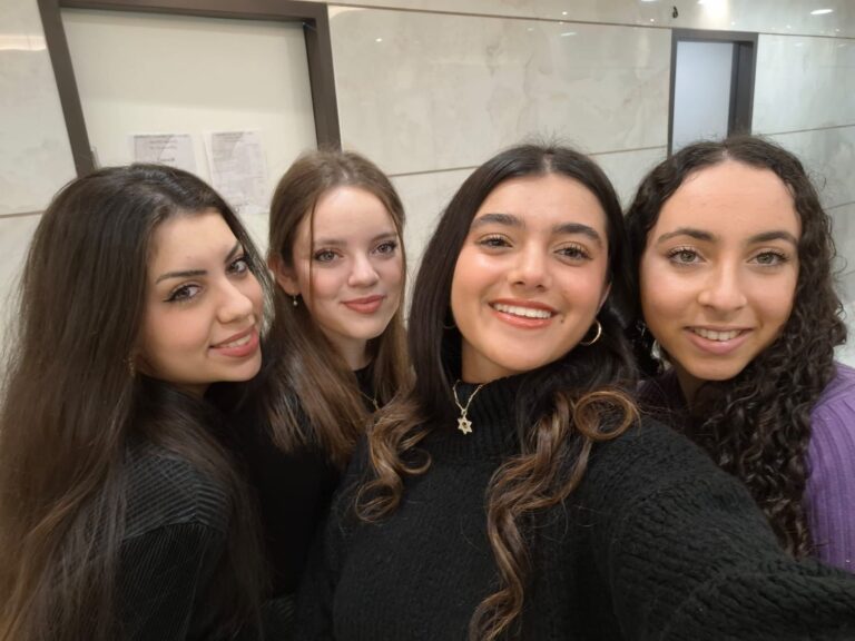Four friends posing in tiled hallway