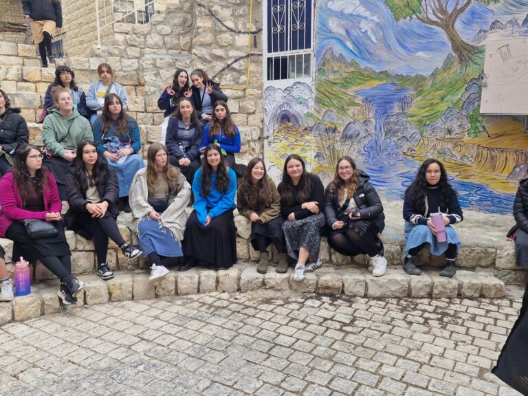 Group seated on stone steps beside colorful mural