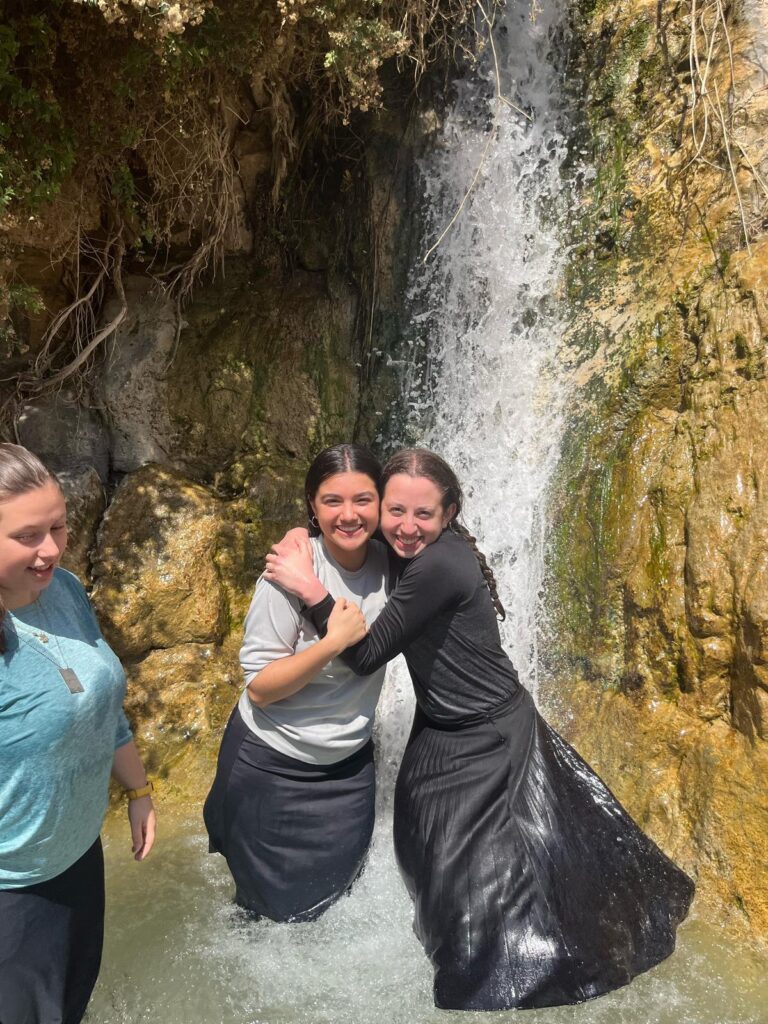 Three friends posing in waterfall pool