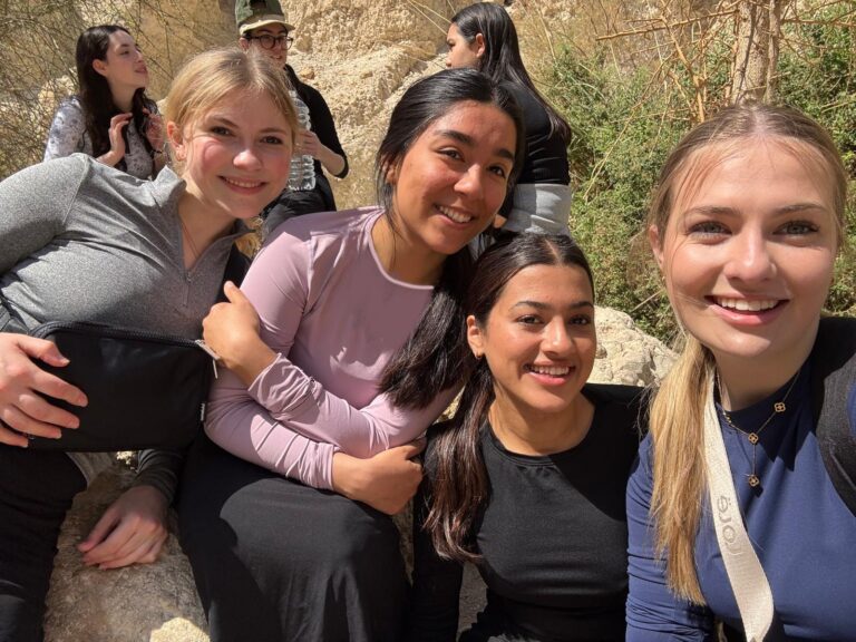 Smiling young women posing outdoors on rocks
