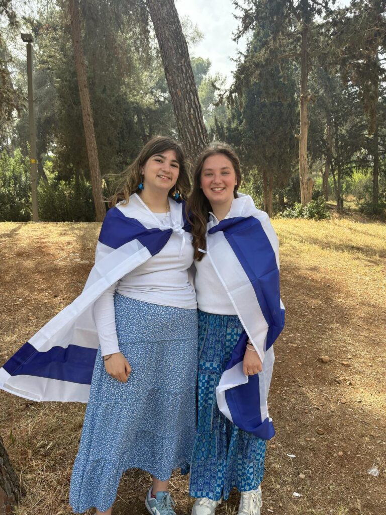 Two smiling women draped in Israeli flags