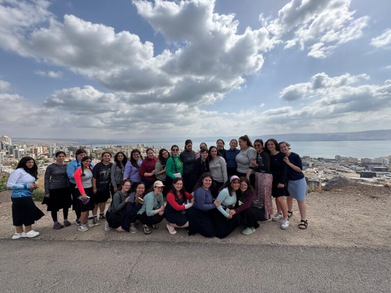Large group posing on hilltop overlooking coastal city