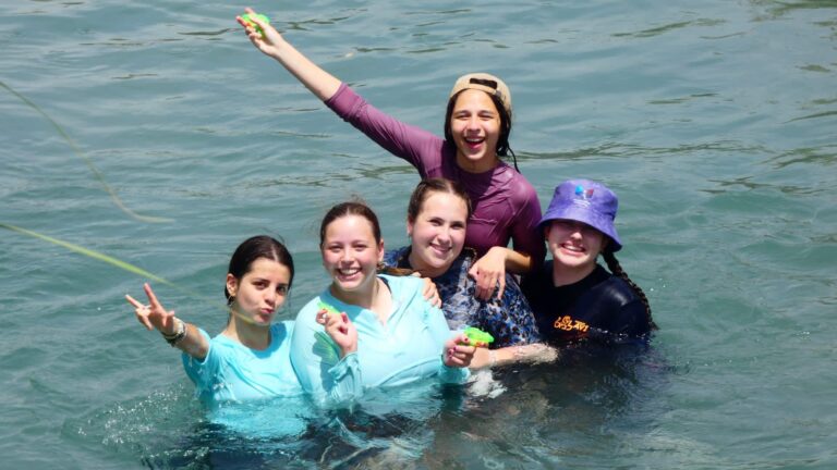 Five friends splashing in water with toys