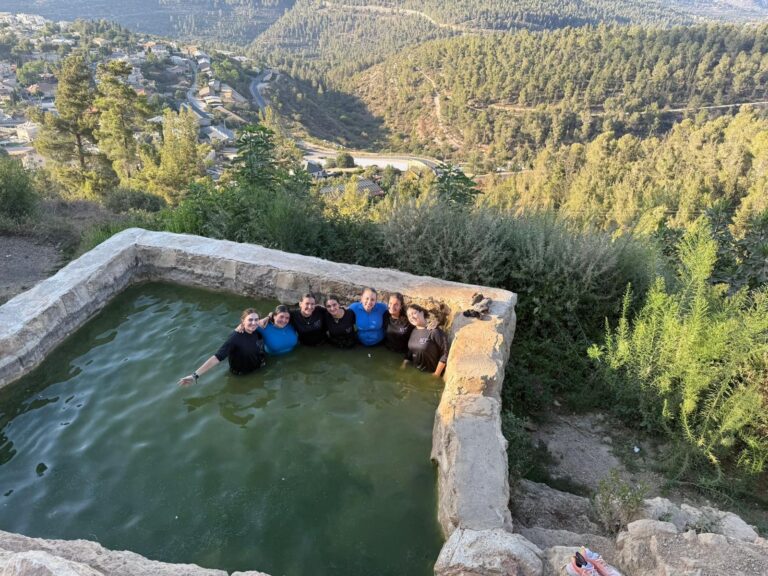 Group in stone hillside pool overlooking valley