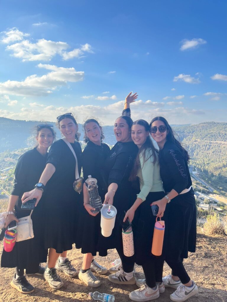 Six friends posing on hillside with water bottles