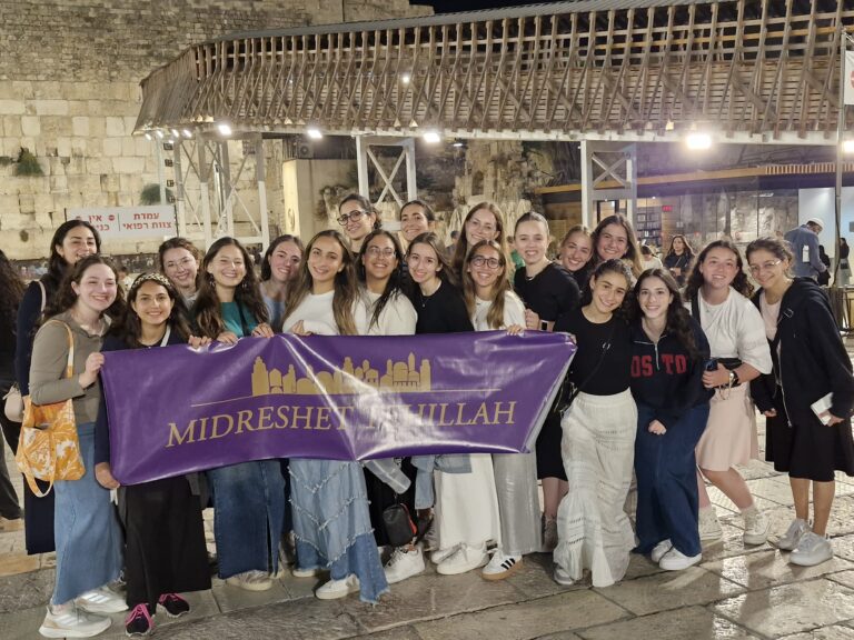 Young women holding purple banner at Western Wall