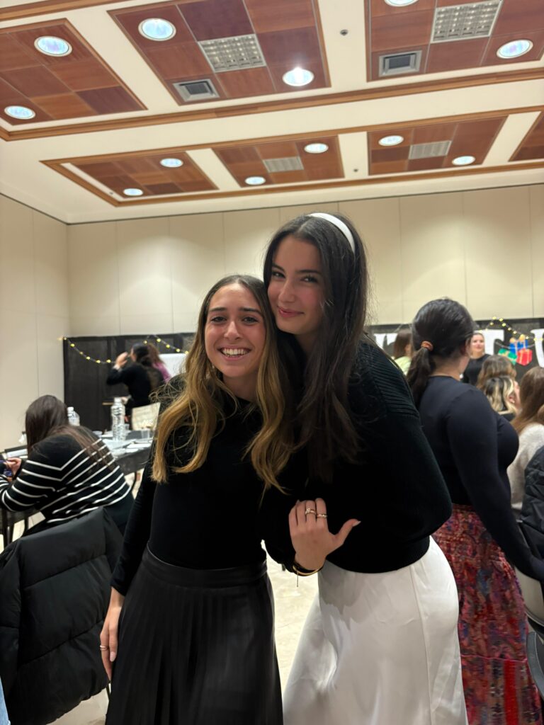 Two smiling women posing at indoor event
