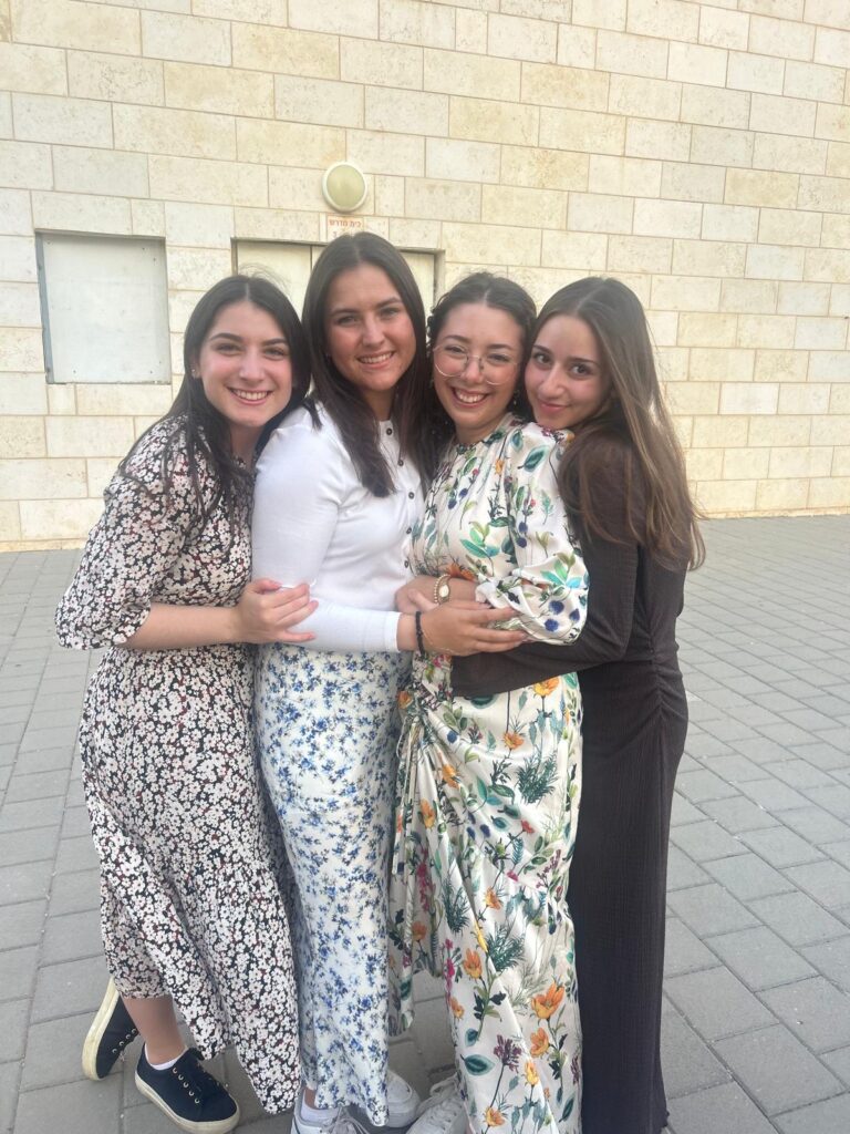 Four smiling women hugging outdoors