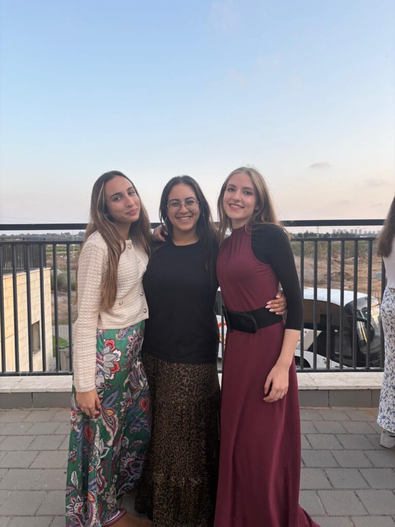 Three women in dresses posing on balcony