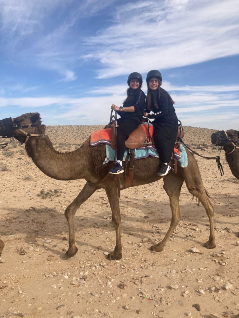 Two people smiling on camel in desert