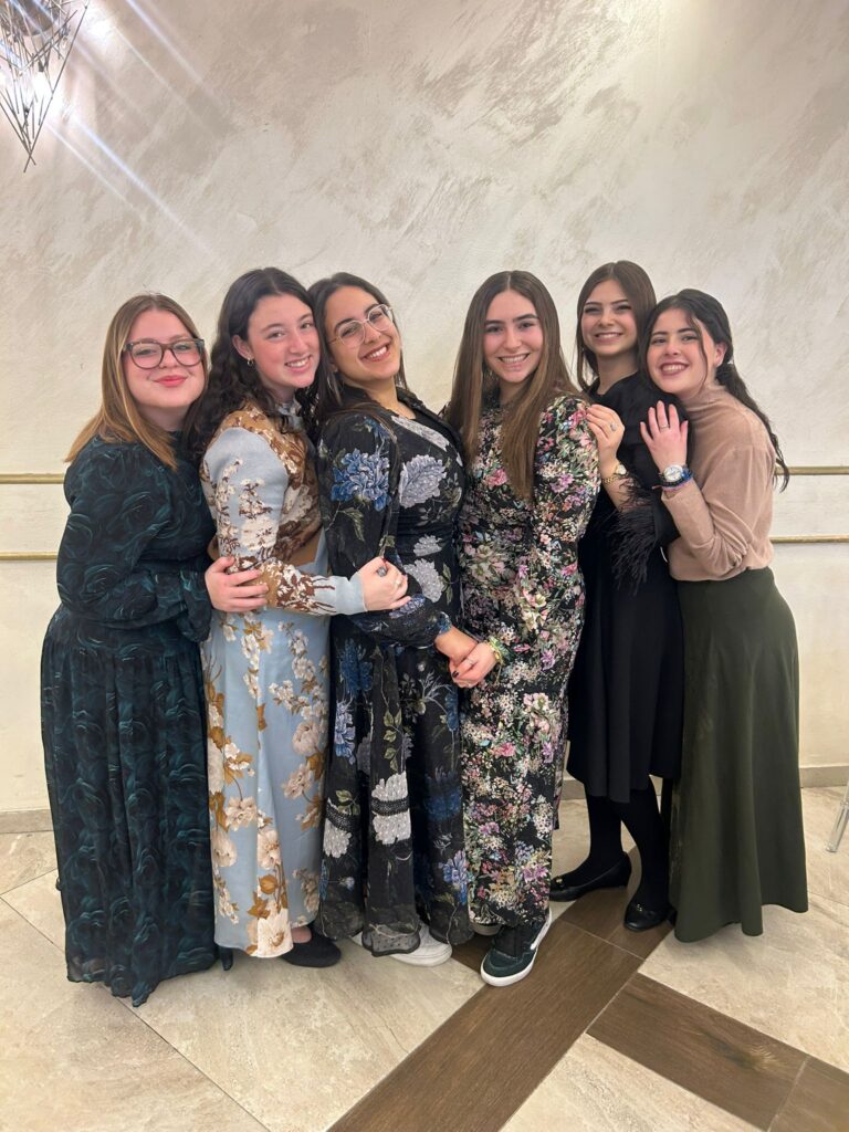 Group of six smiling women in long dresses