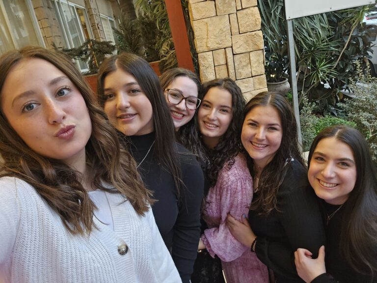 Six friends smiling together in outdoor selfie