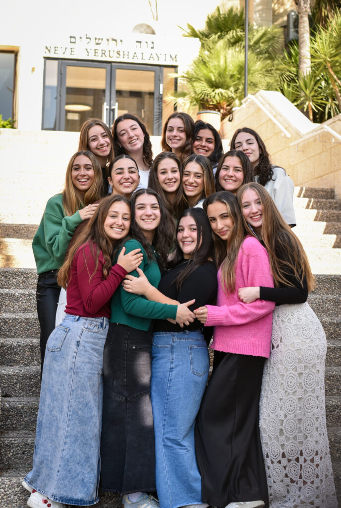 Group of smiling teenage girls hugging on steps