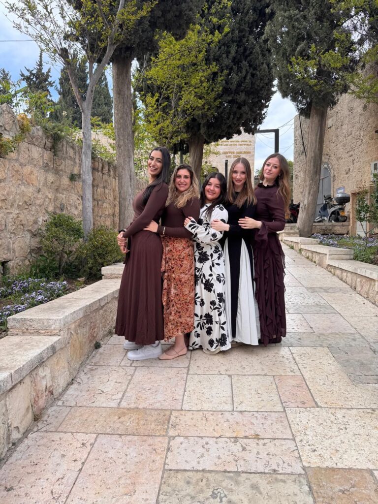 Five women in modest dresses on stone pathway